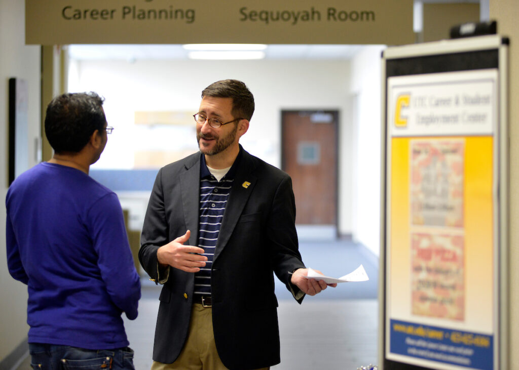 UTC Career coach talking with student in hallway.