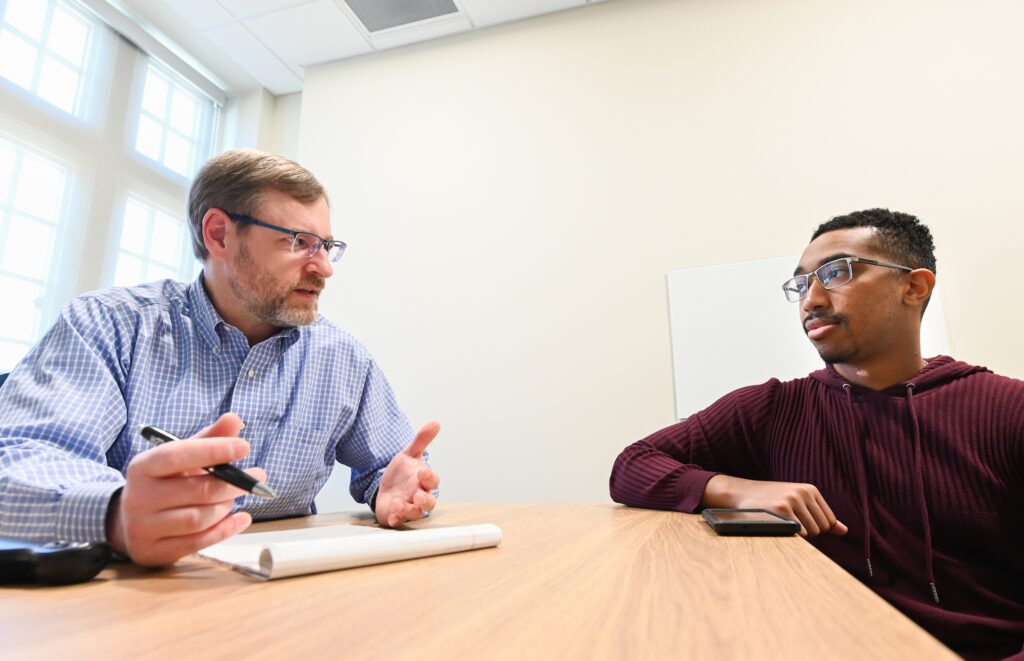 two businessmen talking at a desk
