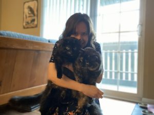 Amy is holding her two cats, Ginger and Wasabi.