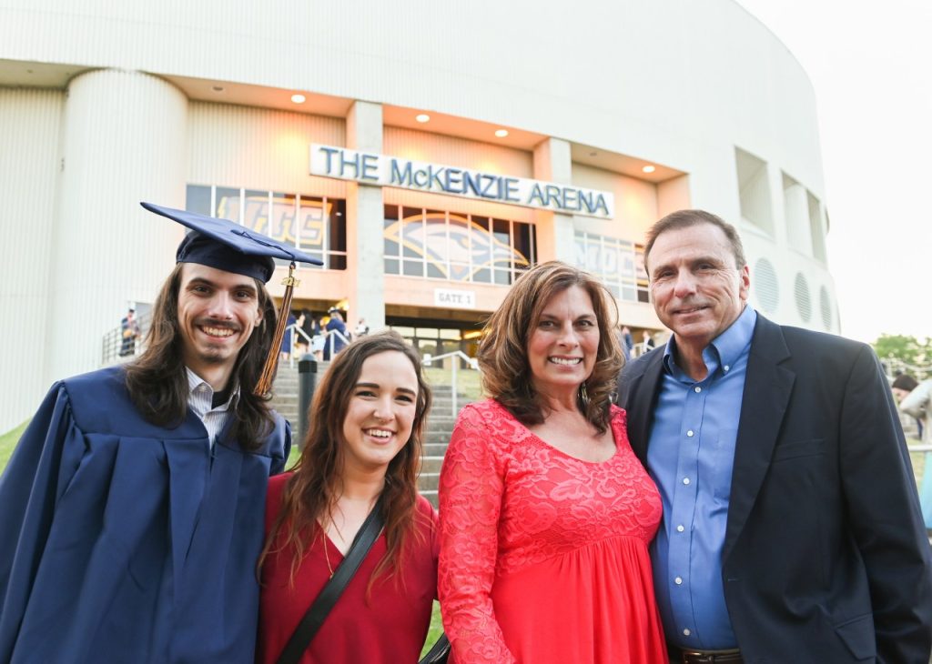 Family members standing outside of Mckenzie Arena with recent graduate.