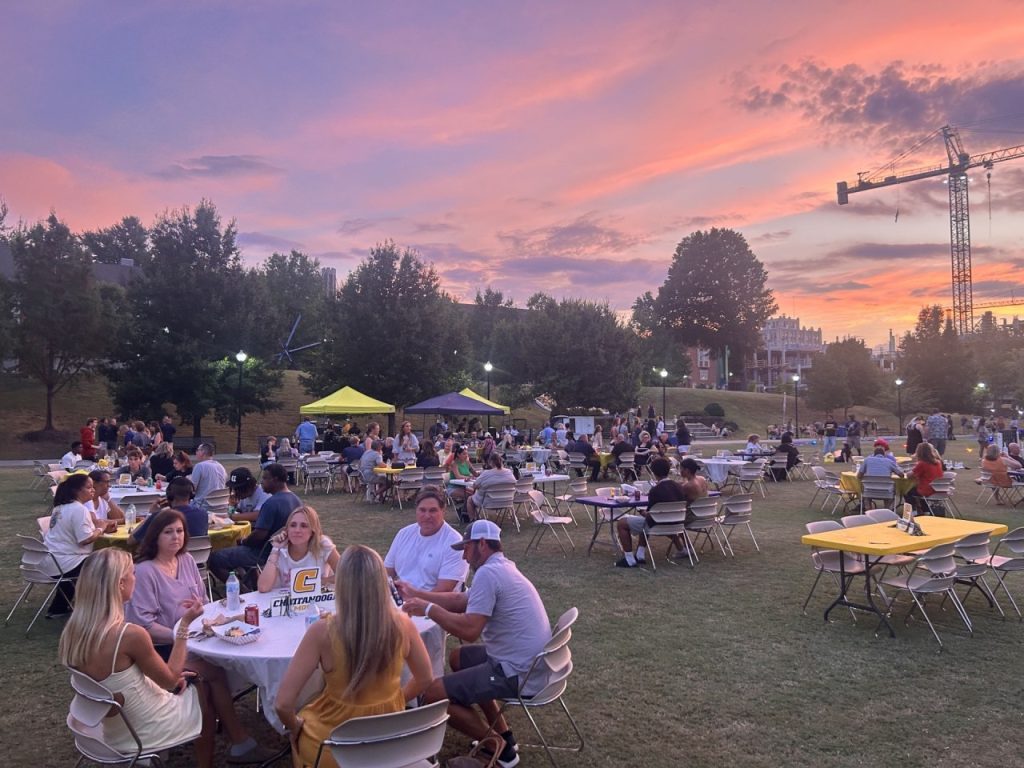Families eating dinner at Fall Family Weekend Kickoff event with pink sunset.