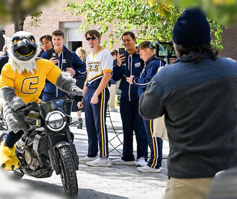 Scrappy on a motorcycle being filmed at a pep-rally
