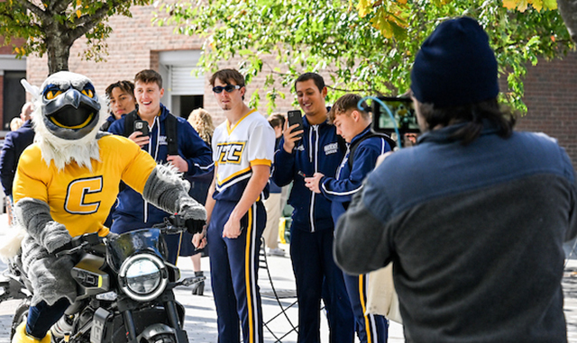 Scrappy on a motorcycle being filmed at a pep-rally
