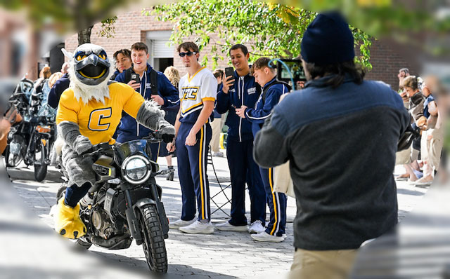 Scrappy on a motorcycle being filmed at a pep-rally