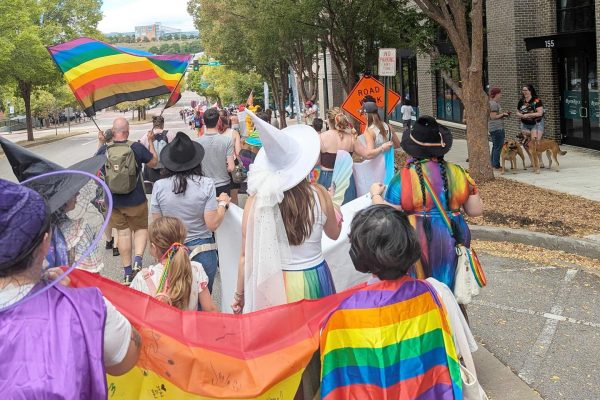 People marching in downtown Chattanooga for October 2025 pride parage. People are waiving pride flags.