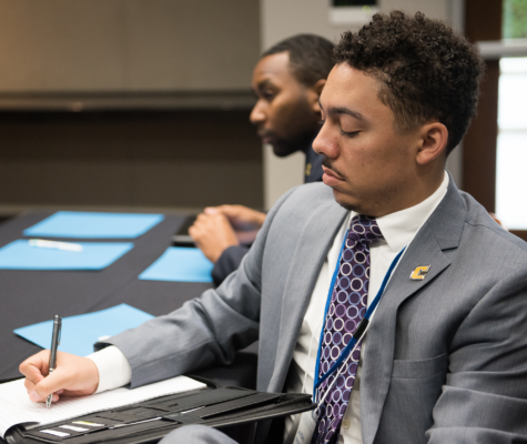Man writing notes in a padfolio.