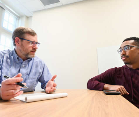 two businessmen talking at a desk