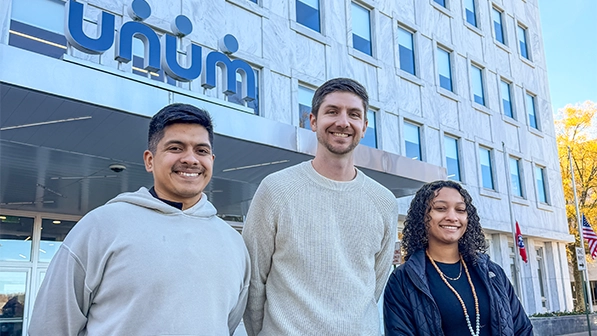 Unum Scholars smile in front of building.
