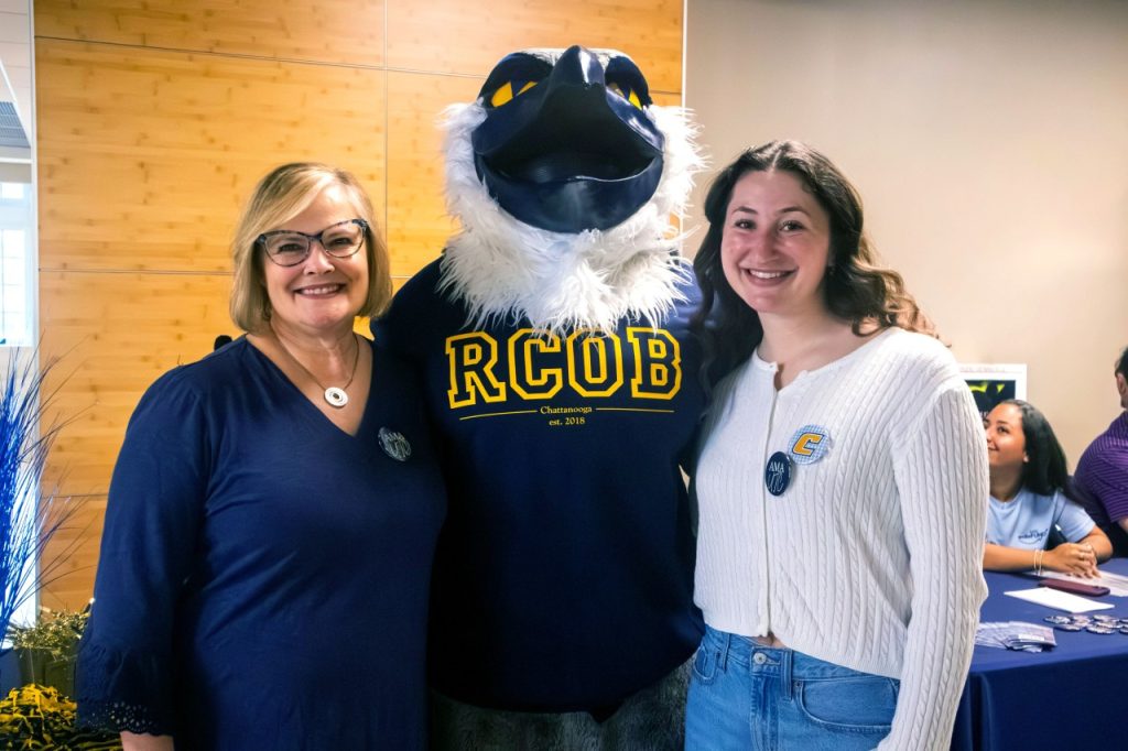 Libby Fakier, Scrappy Moc, and student smile for a photo