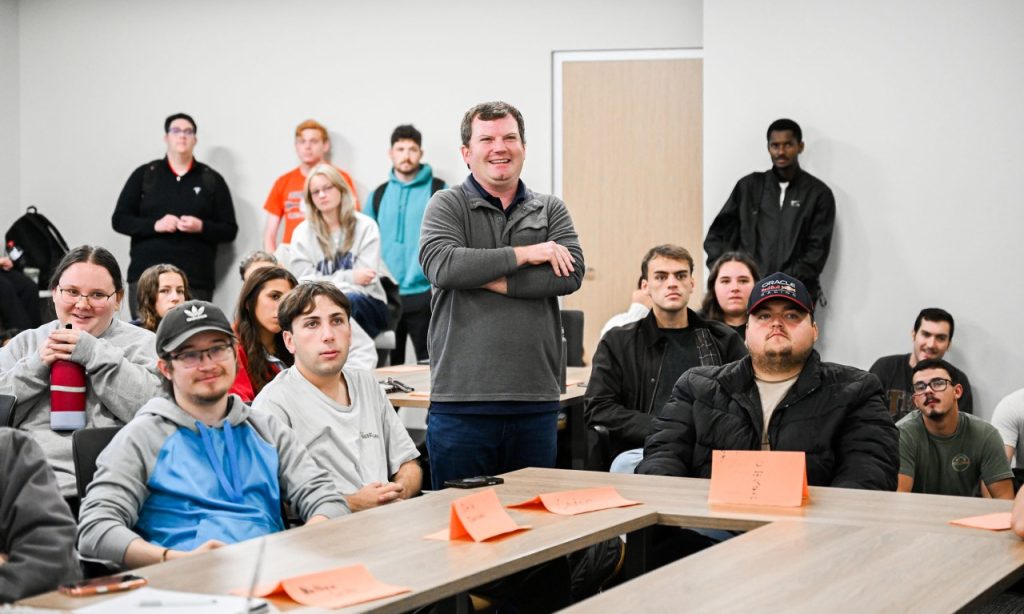 Ryan Russell stands in classroom with students looking at screen