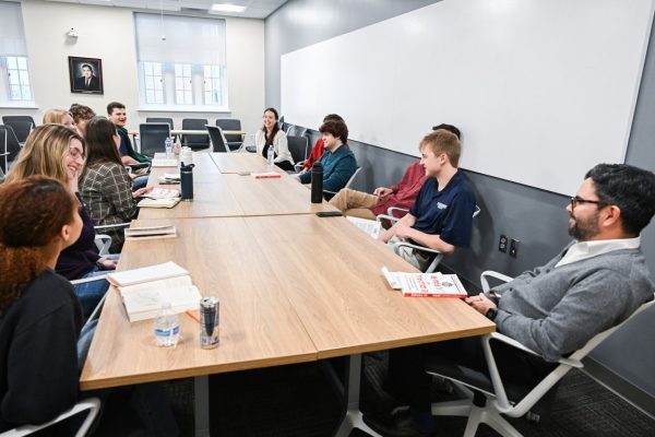 Students sitting around a large table having a discussion and laughing.