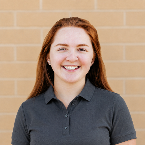 Woman smiling while standing in front of a brick wall