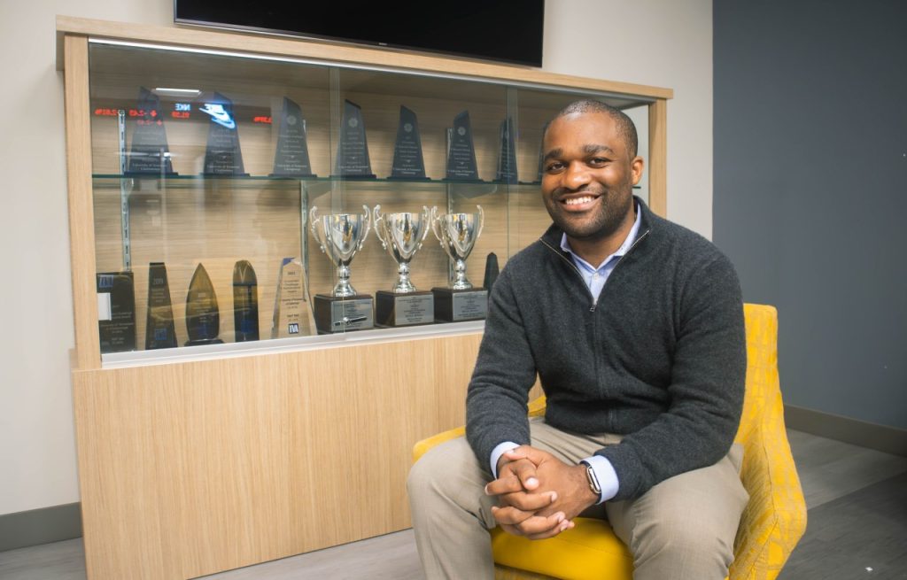 Benjamin Cheatham sits in front of the trophy case outside the Bloomberg Lab at Fletcher Hall.