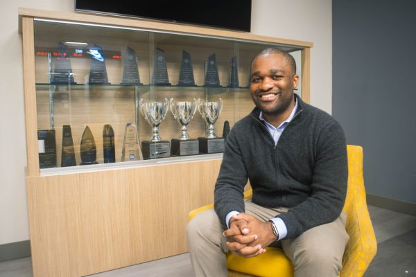 Benjamin Cheatham sits in front of the trophy case outside the Bloomberg Lab at Fletcher Hall.