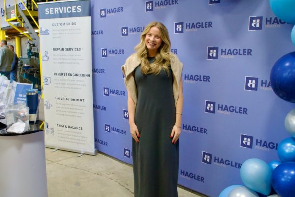 Kristin Lyle stands in front of a wall at Hagler Process smiling for the camera