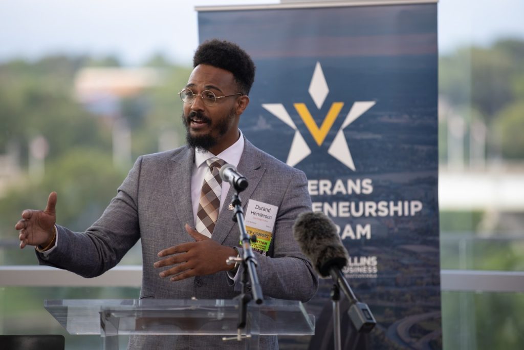 Man wearing gray suit talks at a podium