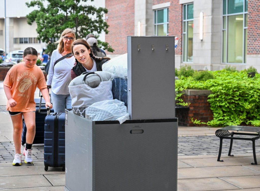 Girl pushes cart in front of residence hall