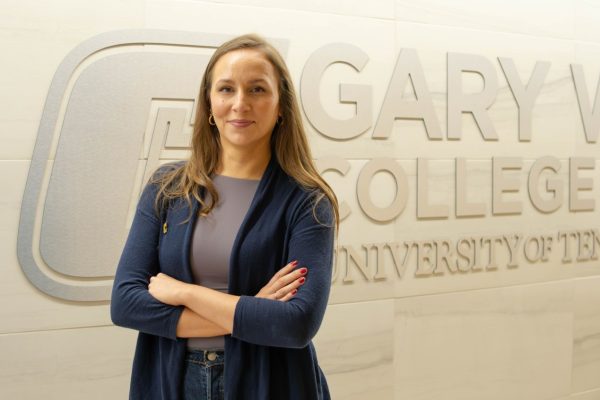 Woman smiling at camera, standing in front of a wall that says Gary W. Rollins College of Business.