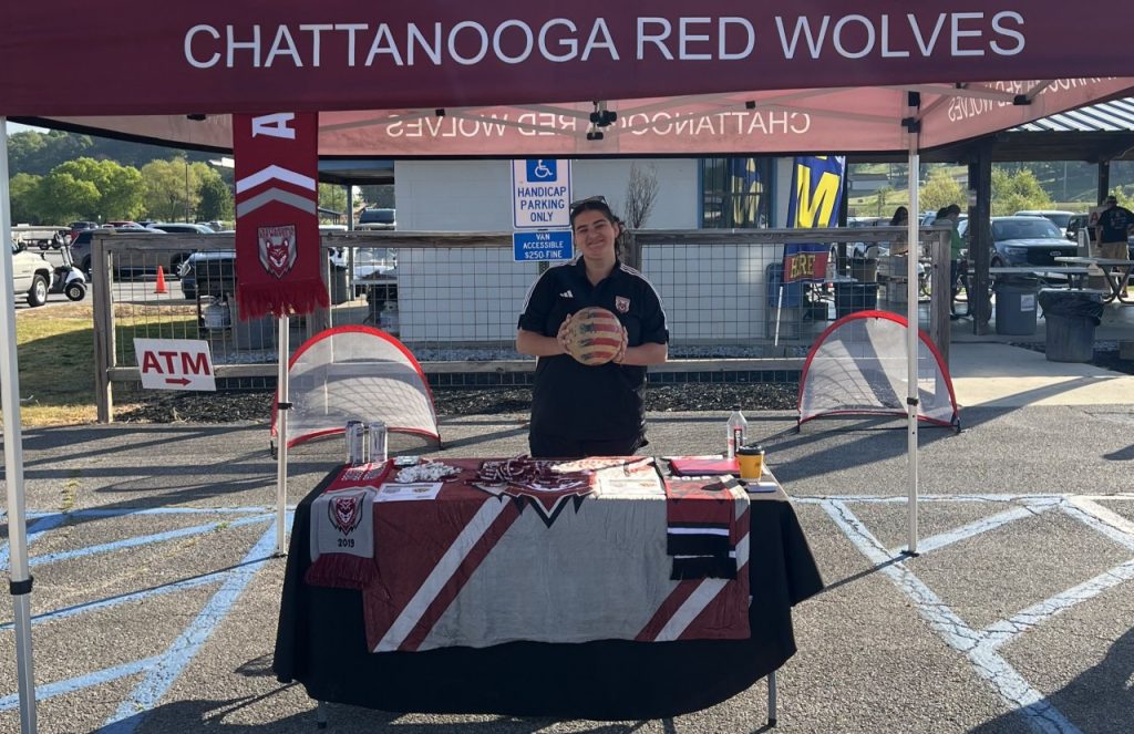 Maia Pentecost poses for a picture under a Red Wolves tent at a community event.