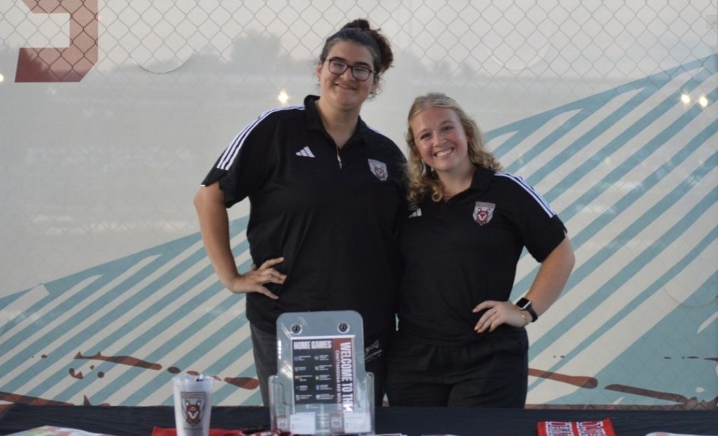 Maia Pentecost and a Red Wolves co-worker pose for a picture at a community event.