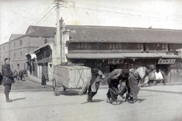 A photograph of men pulling a wheelbarrow