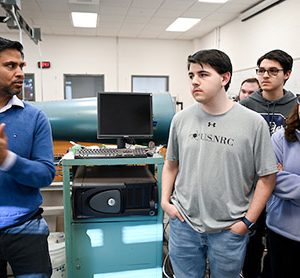 Dr. Reetesh Ranjan is talking with students in the fluids lab in the Engineering and Computer Science building.
