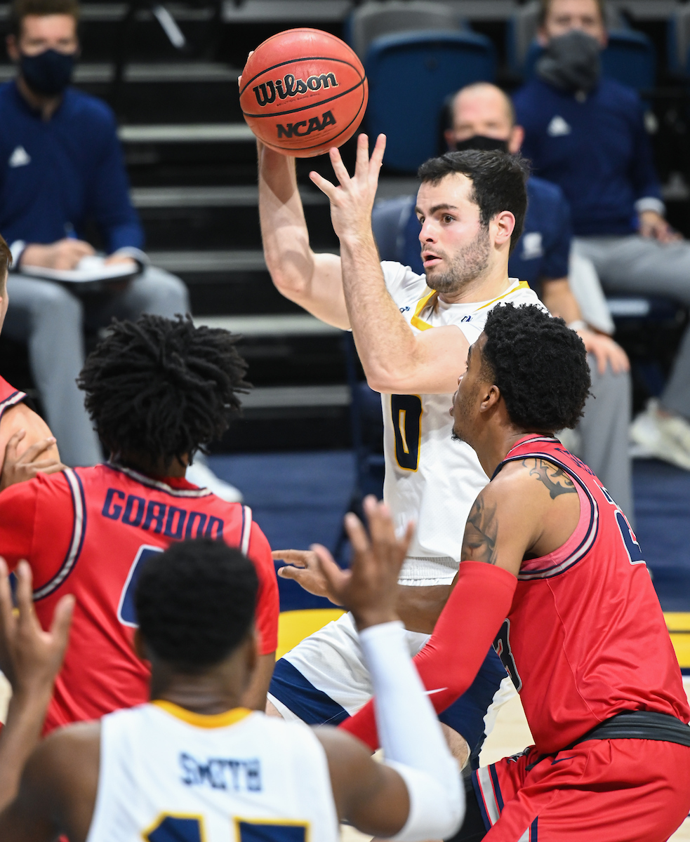 UTC basketball player shoots while guarded by Samford players.