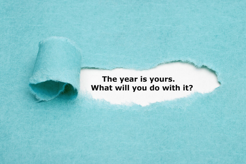 Motivational quote The year is yours. What will you do with it? appearing behind torn blue paper.