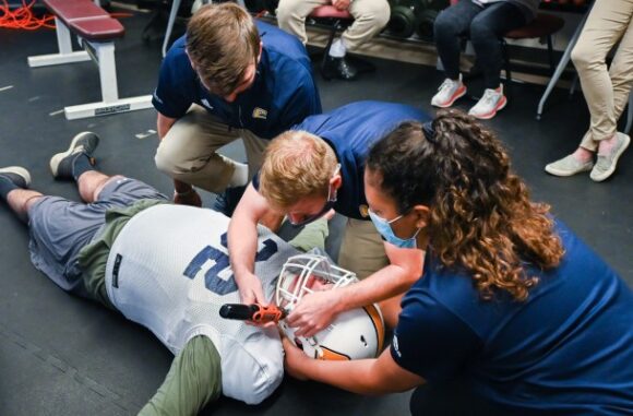 Athletic trainers working on a test dummy football player
