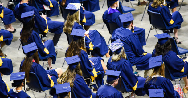 Commencement photo; students sitting in caps and gowns at McKenzie Arena