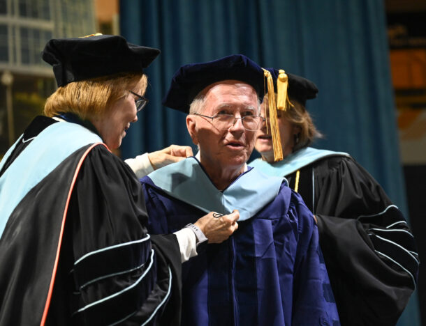 Dr. Tony Galloway is hooded by Dean Valerie Rutledge, left, and Dr. Beth Crawford during UTC Graduate School commencement ceremonies.