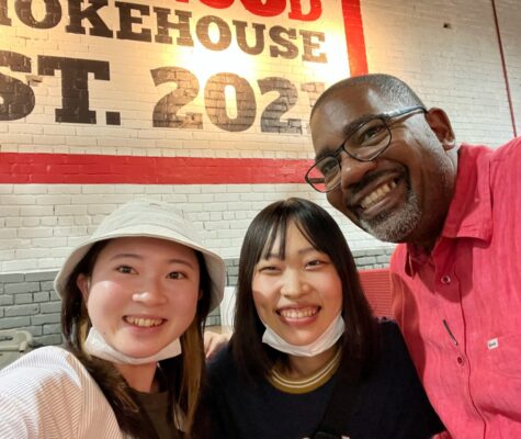 Two students smiling with a restaurant owner