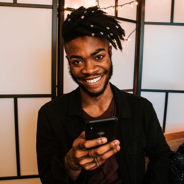 man smiling while holding his cell phone