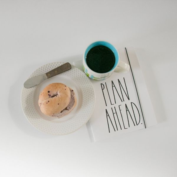a cup of coffee, a planner, and a bagel