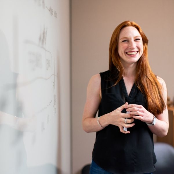 red-headed female teacher in front of a whiteboard