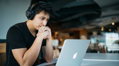 young man with headphones looking at a laptop