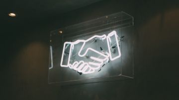 a neon sign of shaking hands
