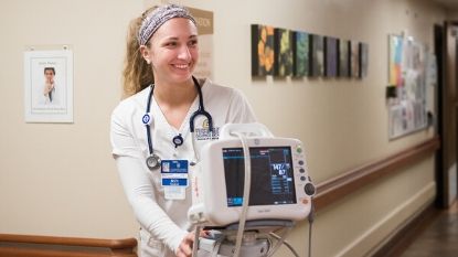 female nurse walking with a machine in a hospital