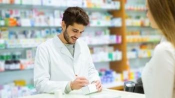 male pharmacy tech giving a prescription to a customer