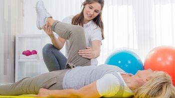 female physical therapy aide stretching out a patient