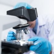 male scientist looking into a microscope in a lab