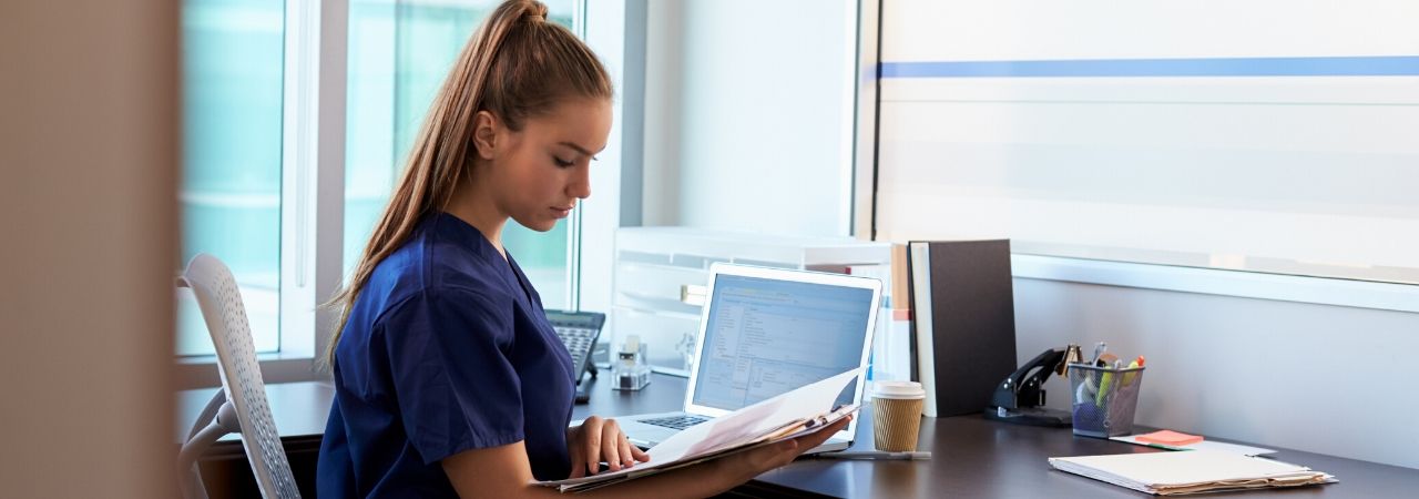 woman looking at medical records next to a computer