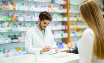male pharmacist writing a prescription for a female customer