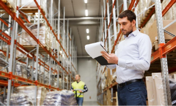 female supply chain manager standing with a clipboard in a warehouse