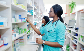 two female pharmacists placing medicine on shelves
