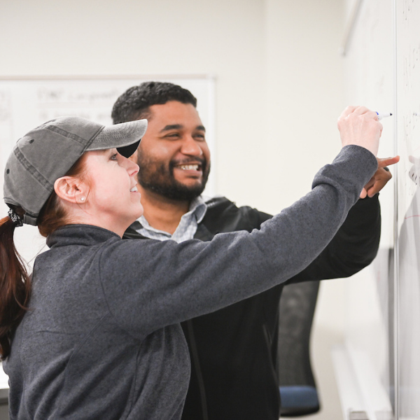 female and male student working on whiteboard together
