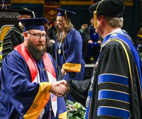 Two people shaking hands on stage at graduation