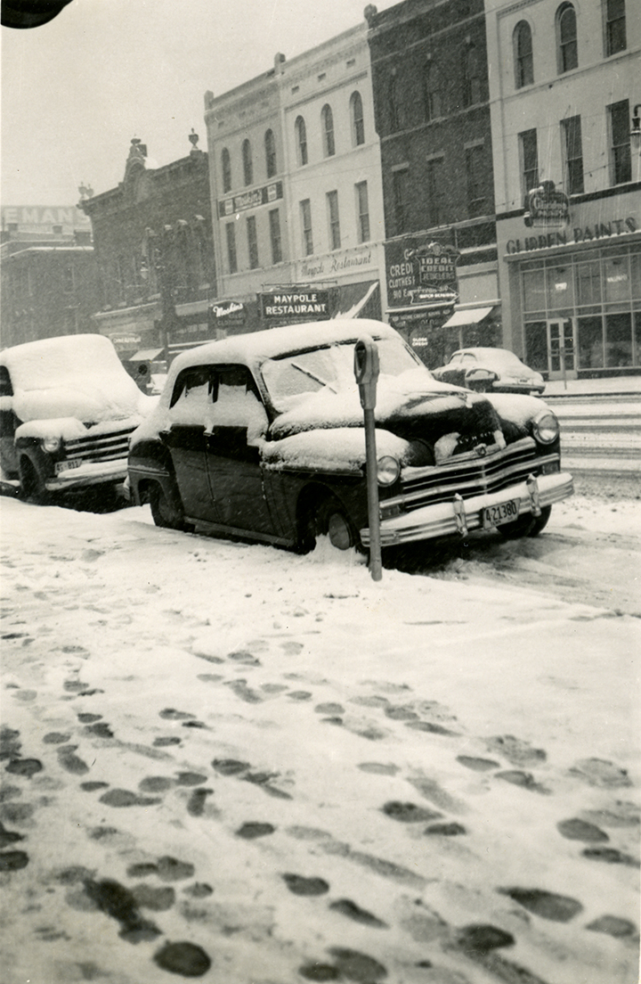 Black-and-white photograph of a car covered in snow in downtown Chattanooga, Tennessee. Photographed by Herman Lamb in 1950.