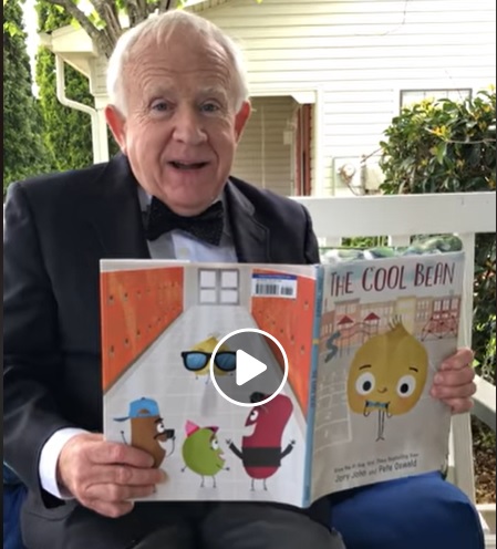 Leslie Jordan sitting on a porch swing holding the book "The Cool Bean"