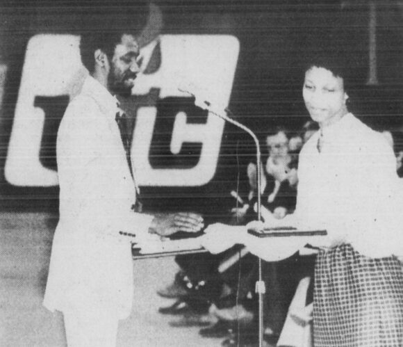 Black-and-white photograph of student Carolyn Delores Higgins approaching podium to accept award.